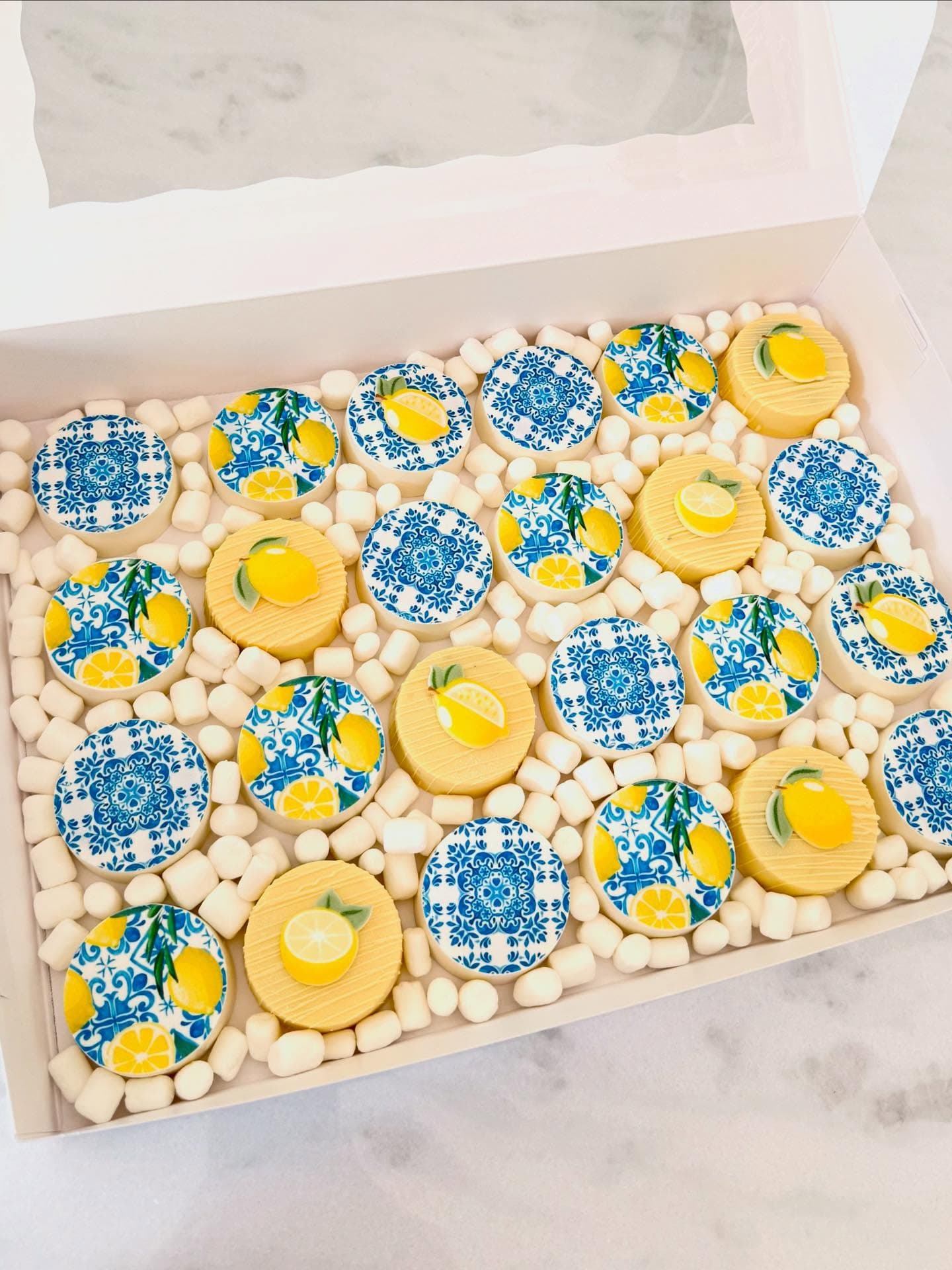 Box of cookies decorated with blue Mediterranean tile patterns and lemons