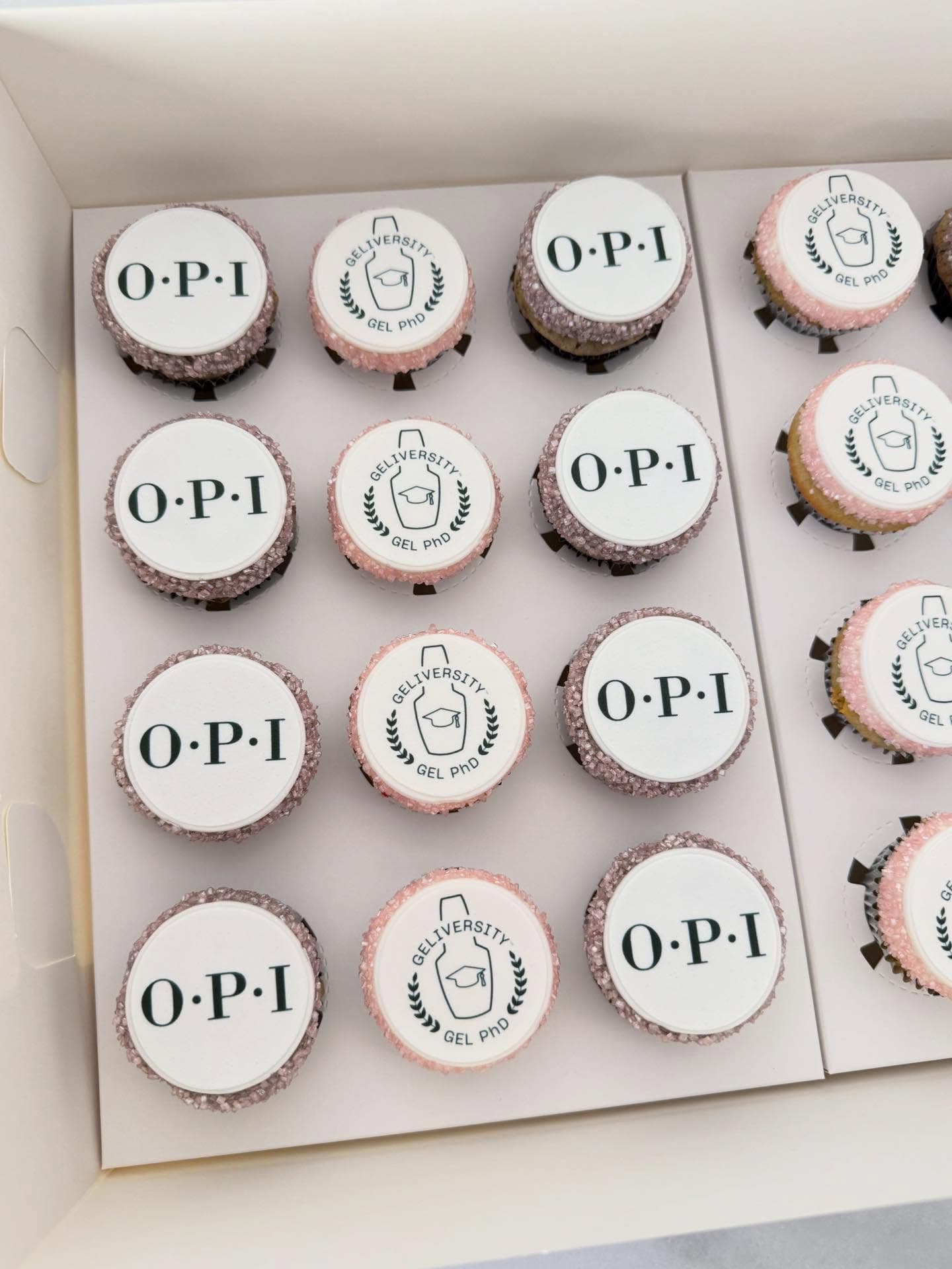 Box of cupcakes with OPI brand edible-print logos and glittered pink edges